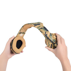 Camouflage headphones held by two hands on a white background
