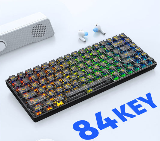 84-key mechanical keyboard on a white surface with earbuds and a speaker in the background.